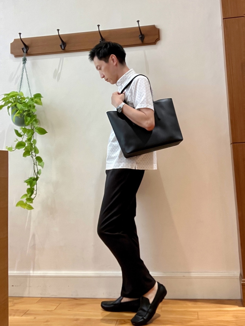ホワイト系のポロシャツ、ブラック系のトートバッグ、ブラウン系のその他パンツを着用したメンズの夏コーディネートの3枚目の写真