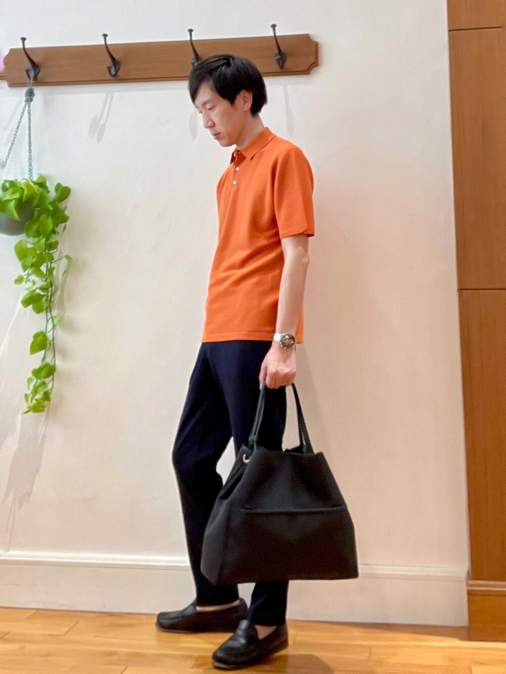 オレンジ系のポロシャツ、ブラック系のトートバッグ、ブルー系のその他パンツを着用したメンズの春コーディネートの2枚目の写真