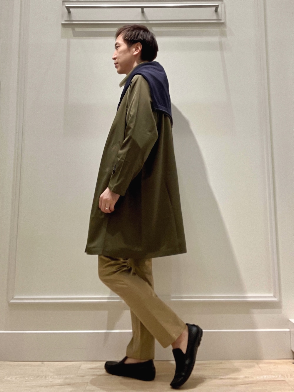 グリーン系のステンカラーコート、ベージュ系のチノパンツ、ブルー系のカーディガン/ボレロを着用したメンズの冬コーディネートの3枚目の写真