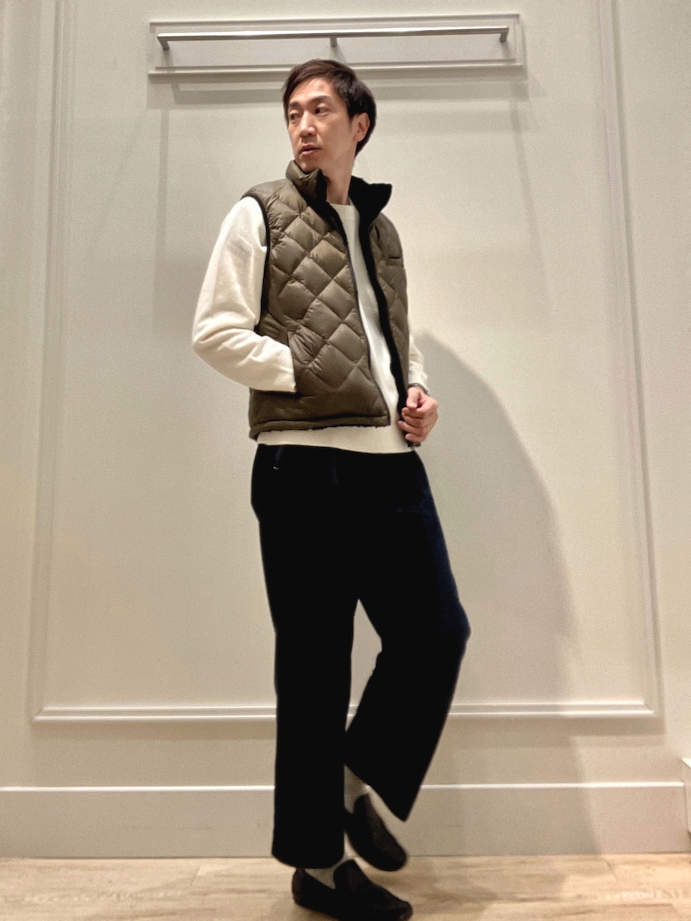 グリーン系のダウンベスト、ホワイト系のニット/セーターを着用したメンズの冬コーディネートの5枚目の写真