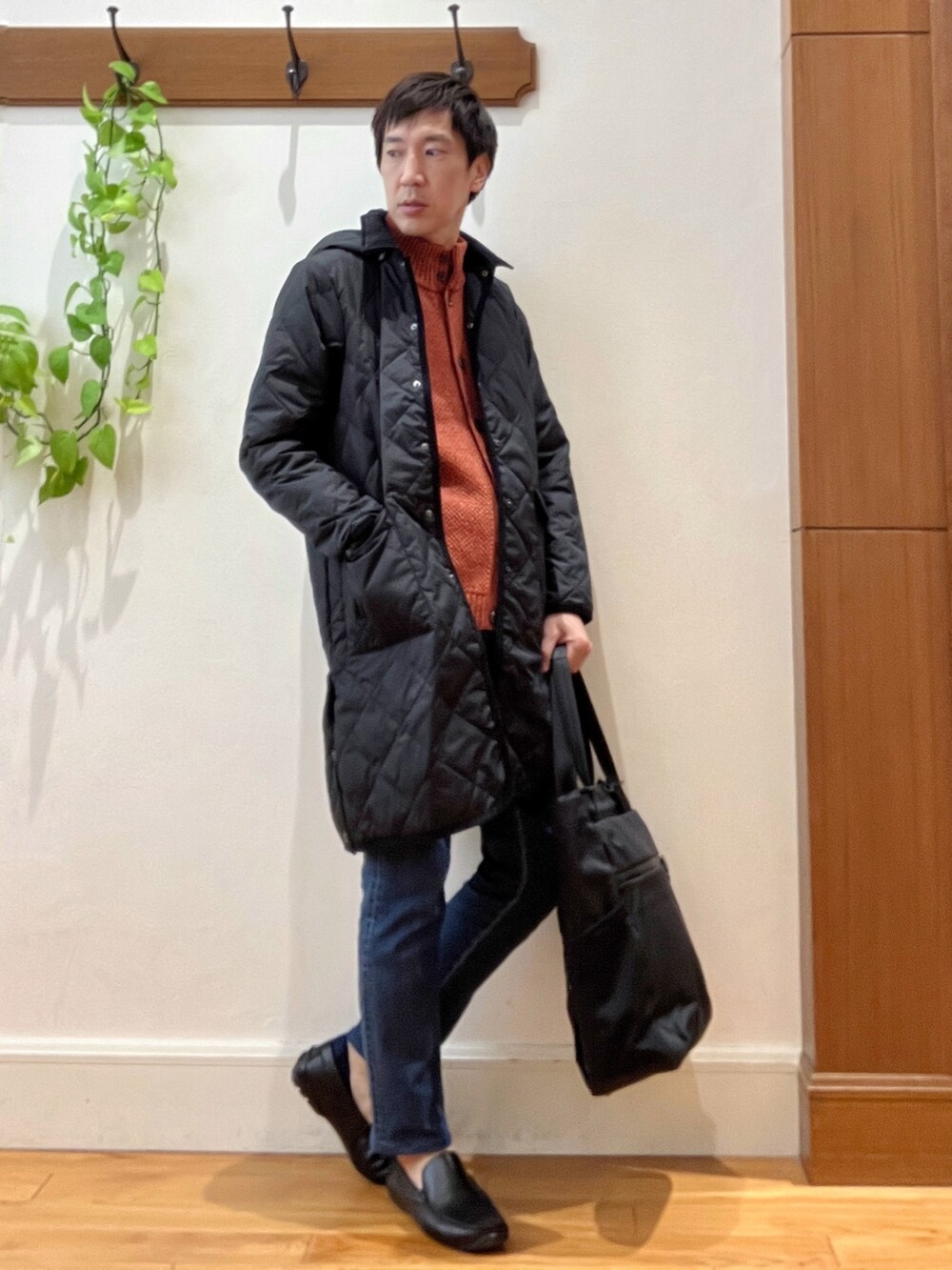 ブラック系のダウンジャケット/コート、オレンジ系のカーディガン/ボレロ、ブラック系のトートバッグを着用したメンズの秋コーディネートの7枚目の写真