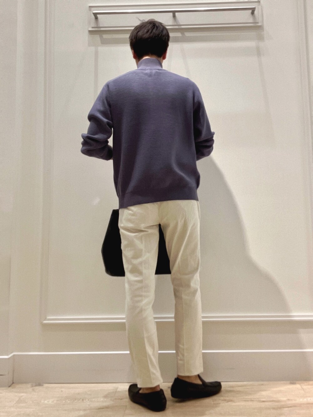 ブルー系のニット/セーター、ブラック系のトートバッグ、ホワイト系のチノパンツを着用したメンズの冬コーディネートの5枚目の写真