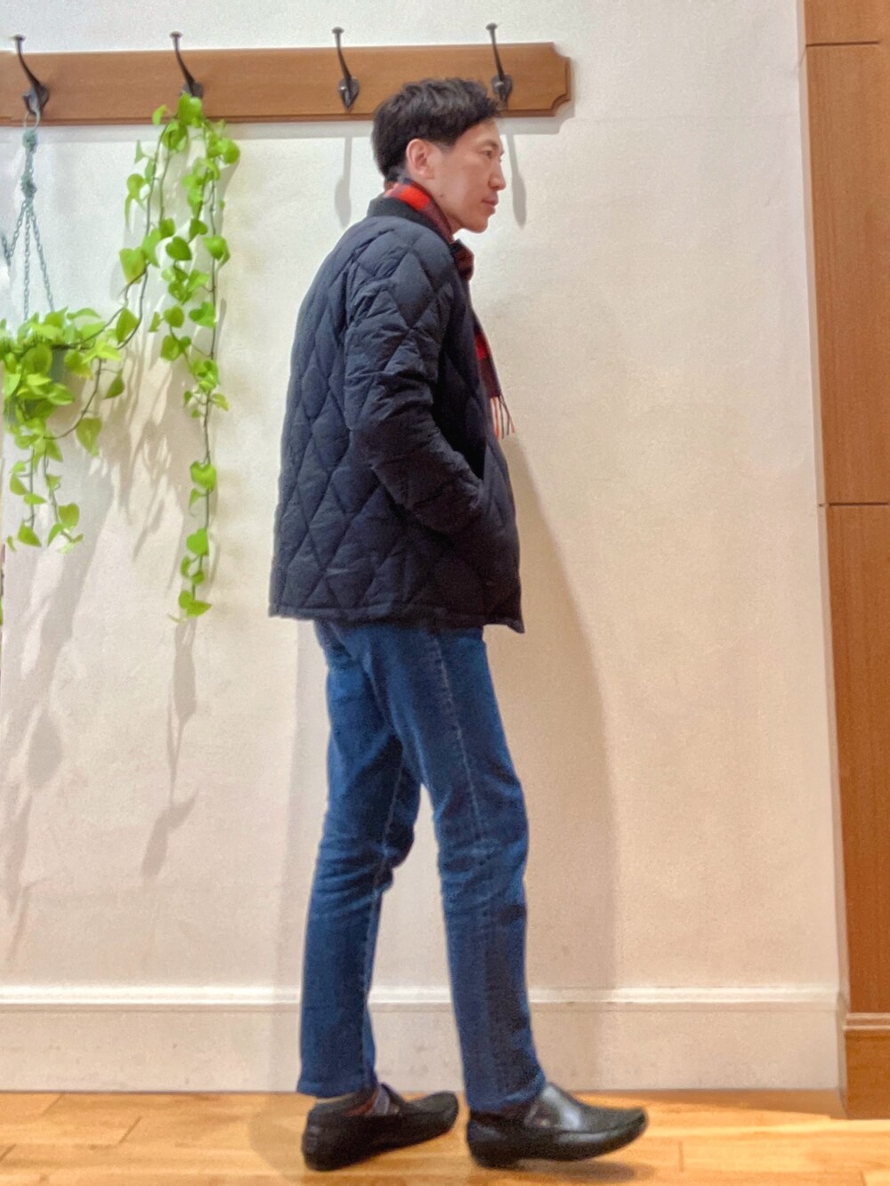 ブラック系のダウンジャケット/コート、ベージュ系のニット/セーター、ブルー系のデニムパンツを着用したメンズの冬コーディネートの5枚目の写真