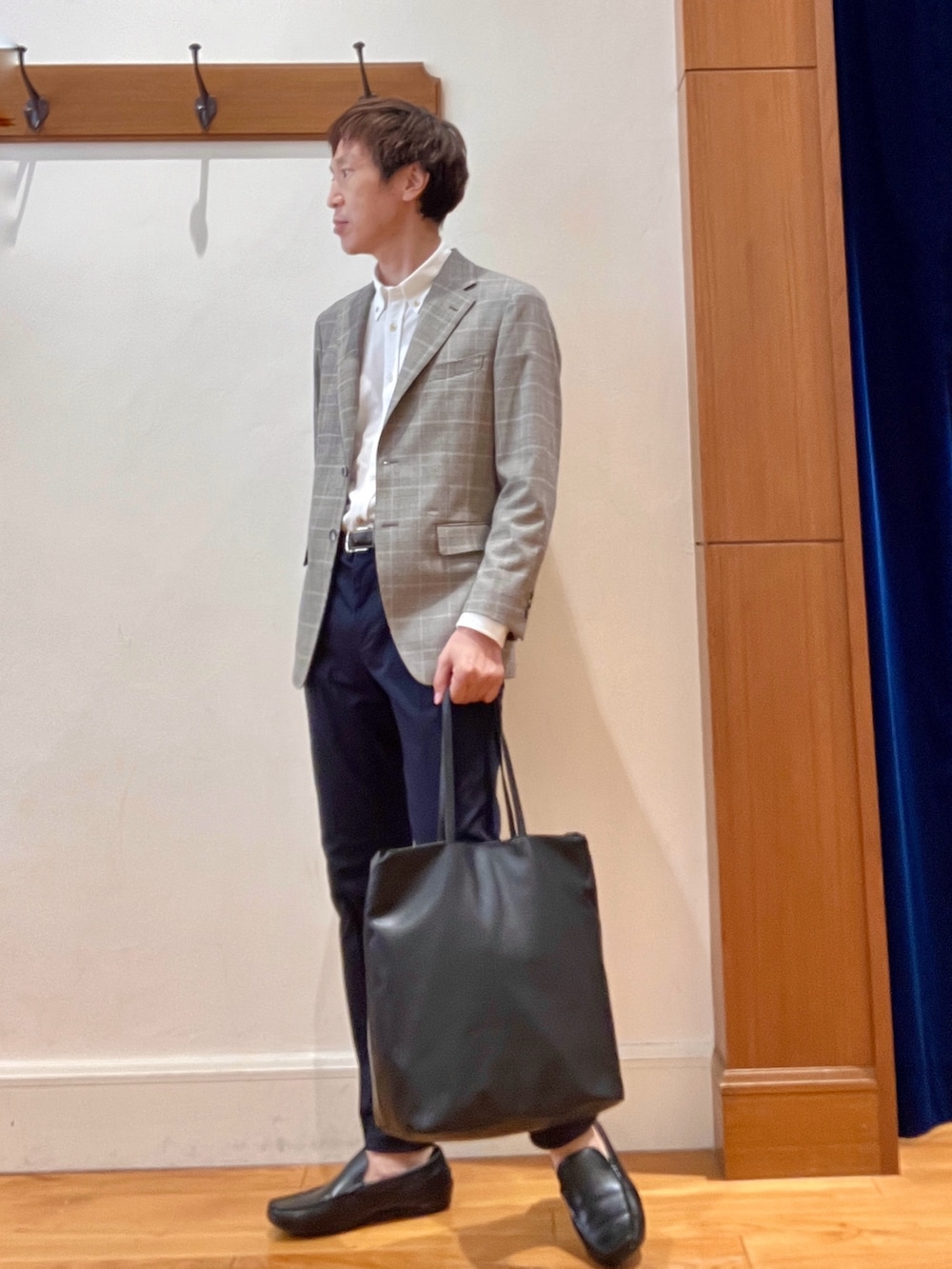 ブラック系のトートバッグ、ブルー系のチノパンツ、ブラウン系のテーラードジャケットを着用したメンズの夏コーディネートの2枚目の写真