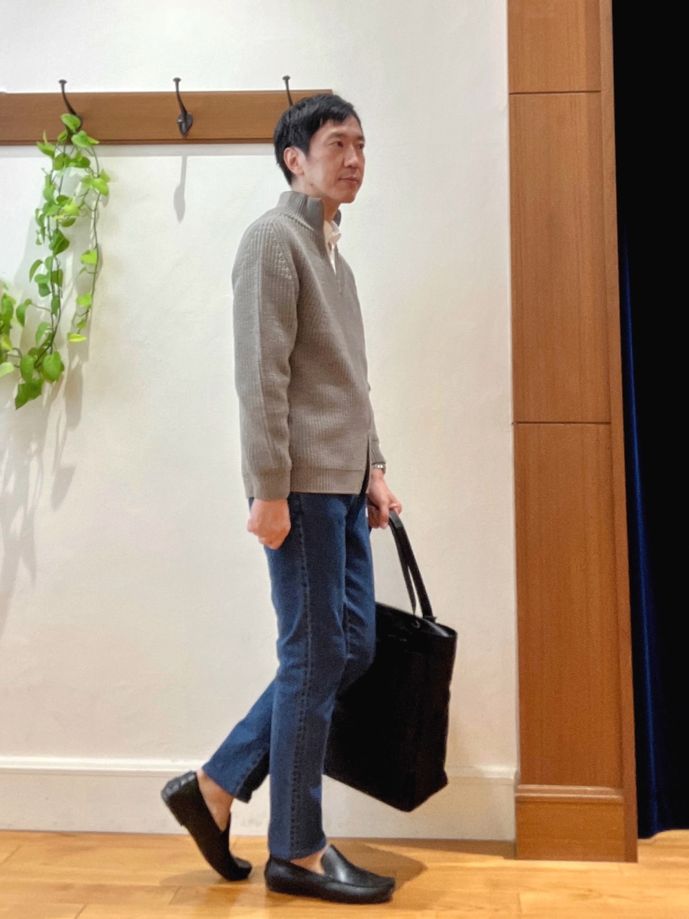 グレー系のニット/セーター、ホワイト系のシャツ/ブラウス、ブルー系のデニムパンツを着用したメンズの秋コーディネートの5枚目の写真