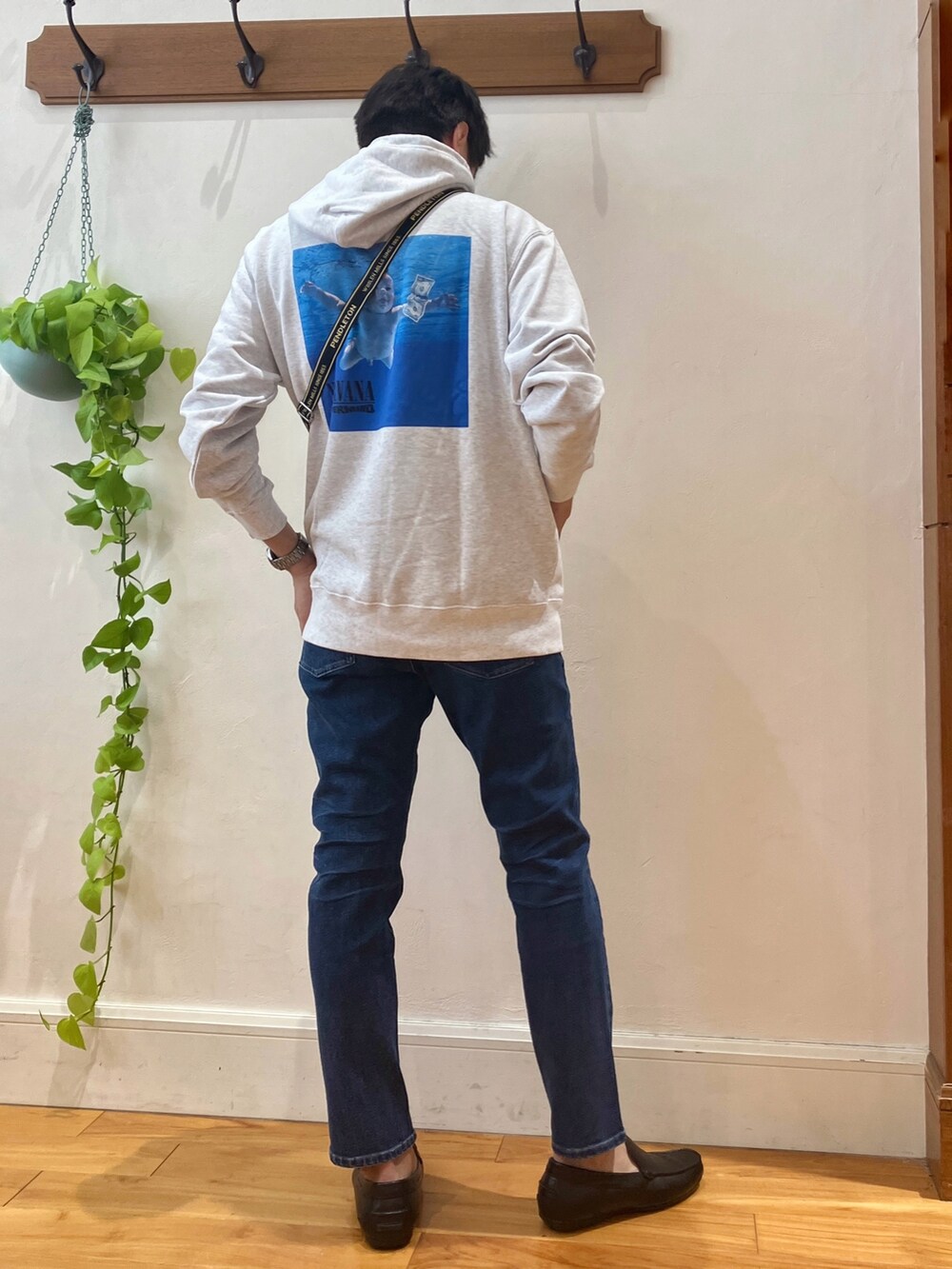 グレー系のパーカー、ブラック系のショルダーバッグ、ブルー系のデニムパンツを着用したメンズの秋コーディネートの3枚目の写真