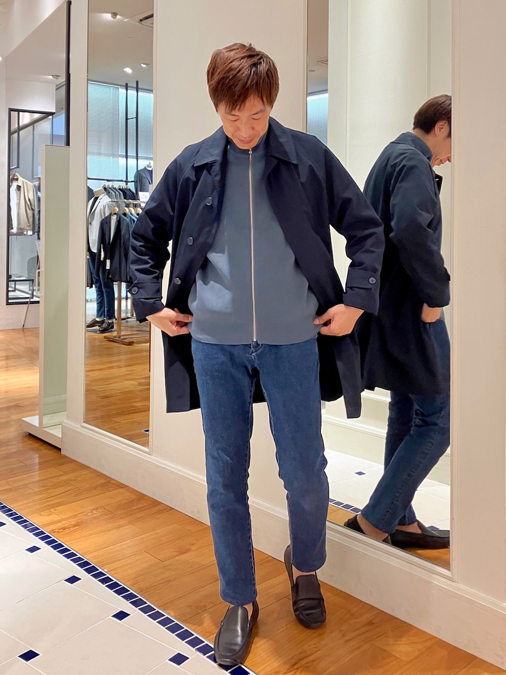 ブルー系のニット/セーター、ブルー系のステンカラーコート、ブルー系のデニムパンツを着用したメンズの秋コーディネートの8枚目の写真