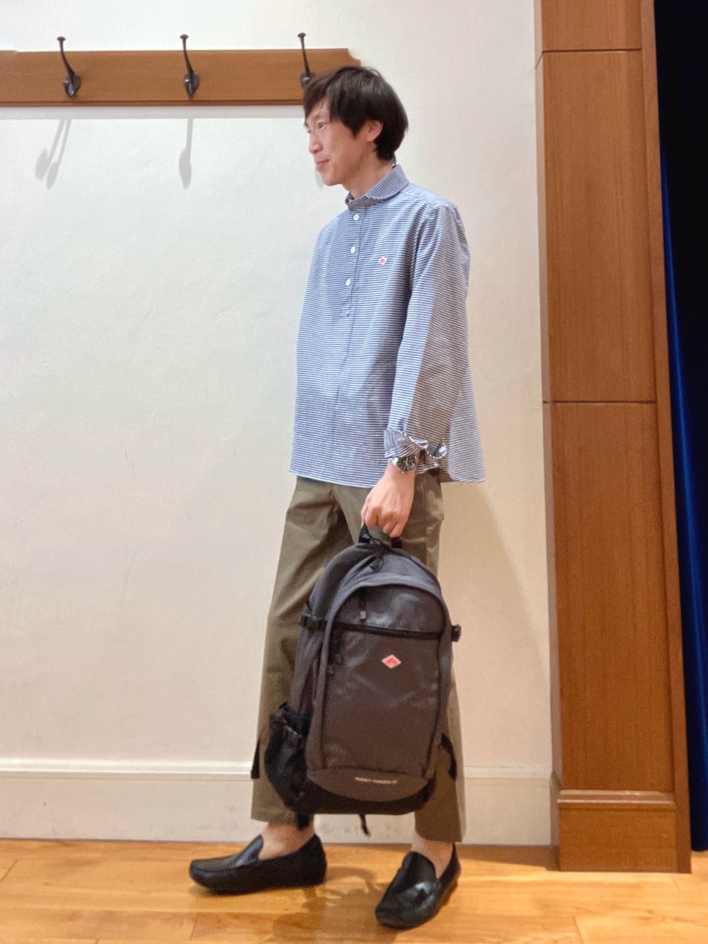 ブルー系のシャツ/ブラウス、グレー系のバックパック/リュック、グリーン系のチノパンツを着用したメンズの春コーディネートの2枚目の写真