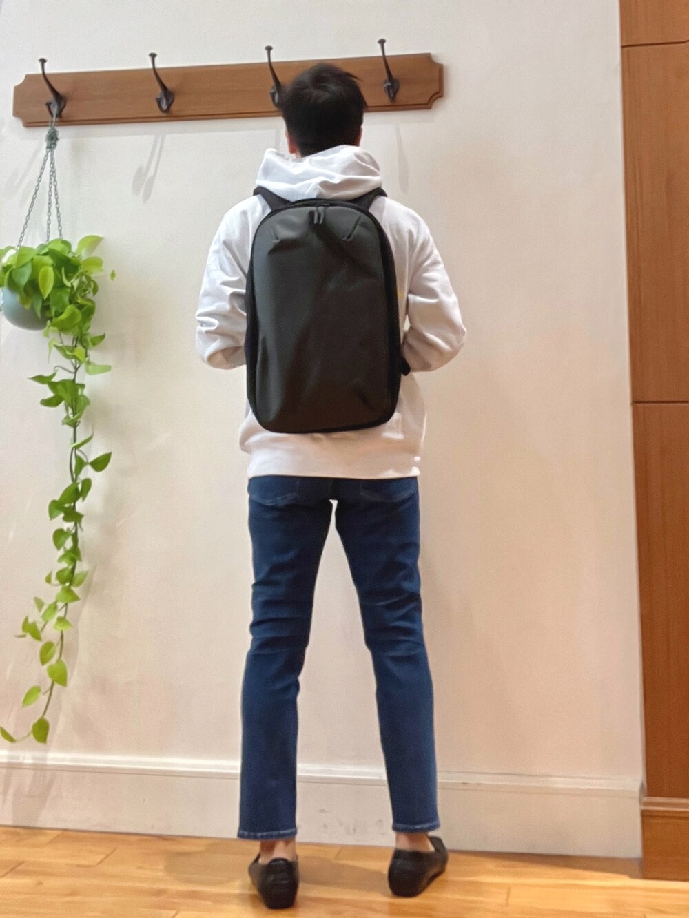 グレー系のパーカー、ブルー系のデニムパンツ、ブラック系のバックパック/リュックを着用したメンズの秋コーディネートの4枚目の写真