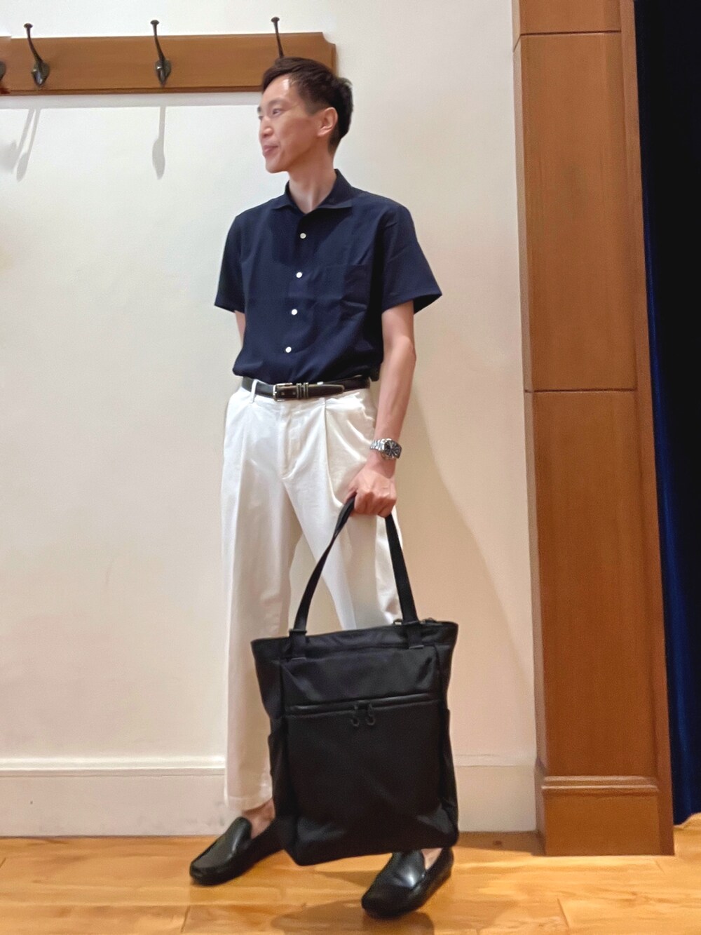 ホワイト系のデニムパンツ、ブルー系のビジネスシャツ、ブラック系のトートバッグを着用したメンズの夏コーディネートの2枚目の写真