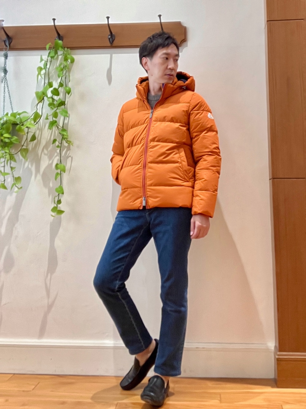 ブルー系のデニムパンツ、ベージュ系のニット/セーター、オレンジ系のダウンジャケット/コートを着用したメンズの冬コーディネートの7枚目の写真