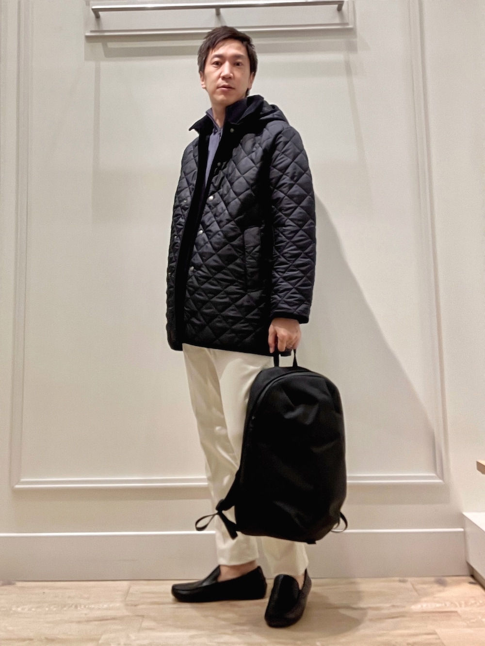 ブルー系のステンカラーコート、ブルー系のニット/セーター、ホワイト系のチノパンツを着用したメンズの冬コーディネートの3枚目の写真