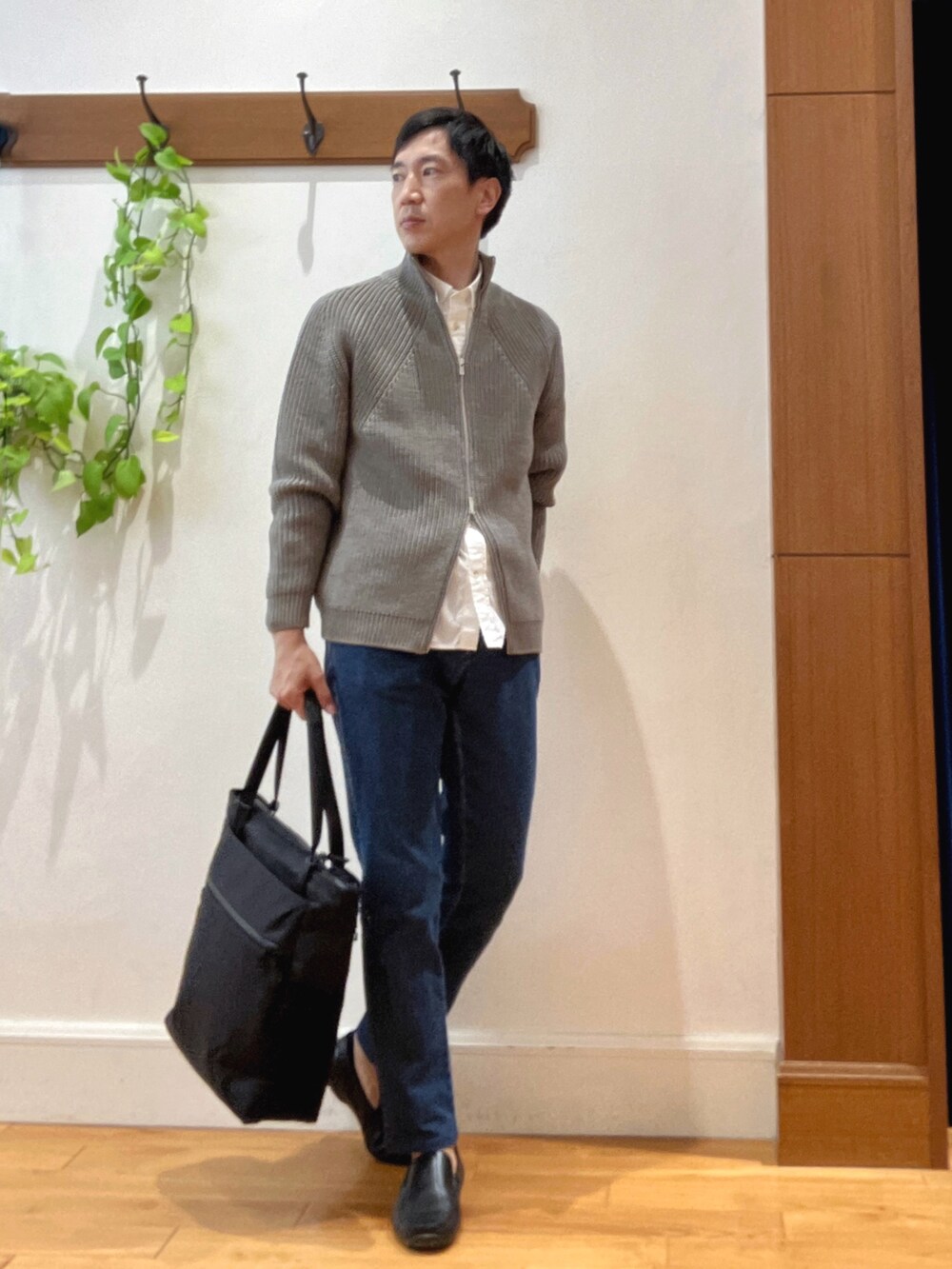 グレー系のニット/セーター、ホワイト系のシャツ/ブラウス、ブルー系のデニムパンツを着用したメンズの秋コーディネートの6枚目の写真