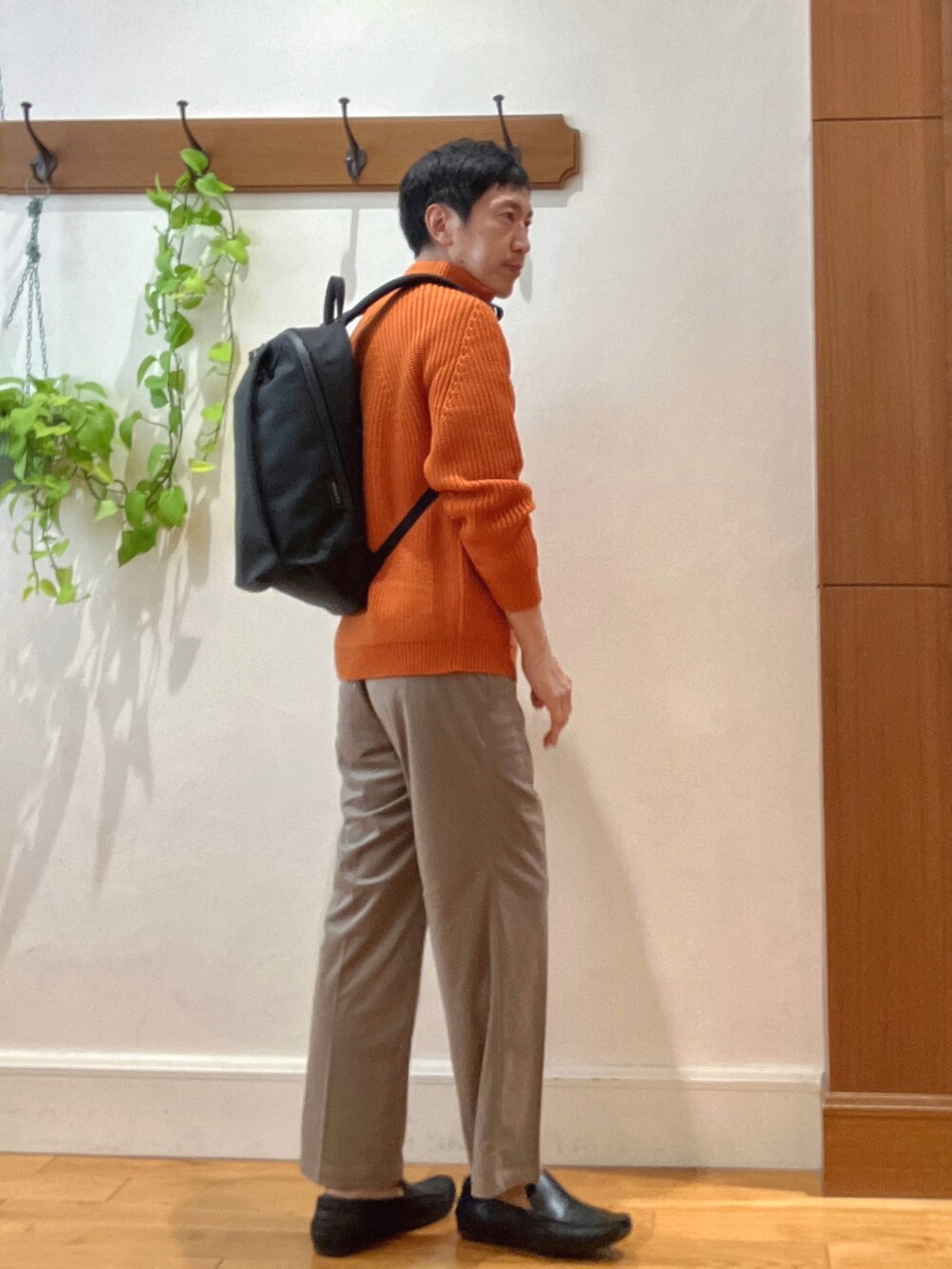 オレンジ系のニット/セーター、ブラック系のバックパック/リュック、ホワイト系のTシャツ/カットソーを着用したメンズの秋コーディネートの5枚目の写真