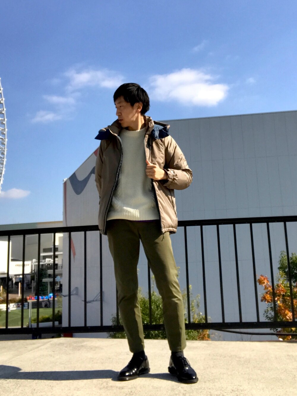 イエロー系のダウンジャケット/コート、ホワイト系のニット/セーター、グリーン系のチノパンツを着用したメンズの冬コーディネートの3枚目の写真