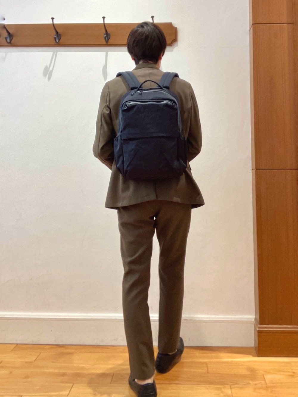 ブラウン系のテーラードジャケット、ブラック系のバックパック/リュック、ブラウン系のその他パンツを着用したメンズの春コーディネートの5枚目の写真