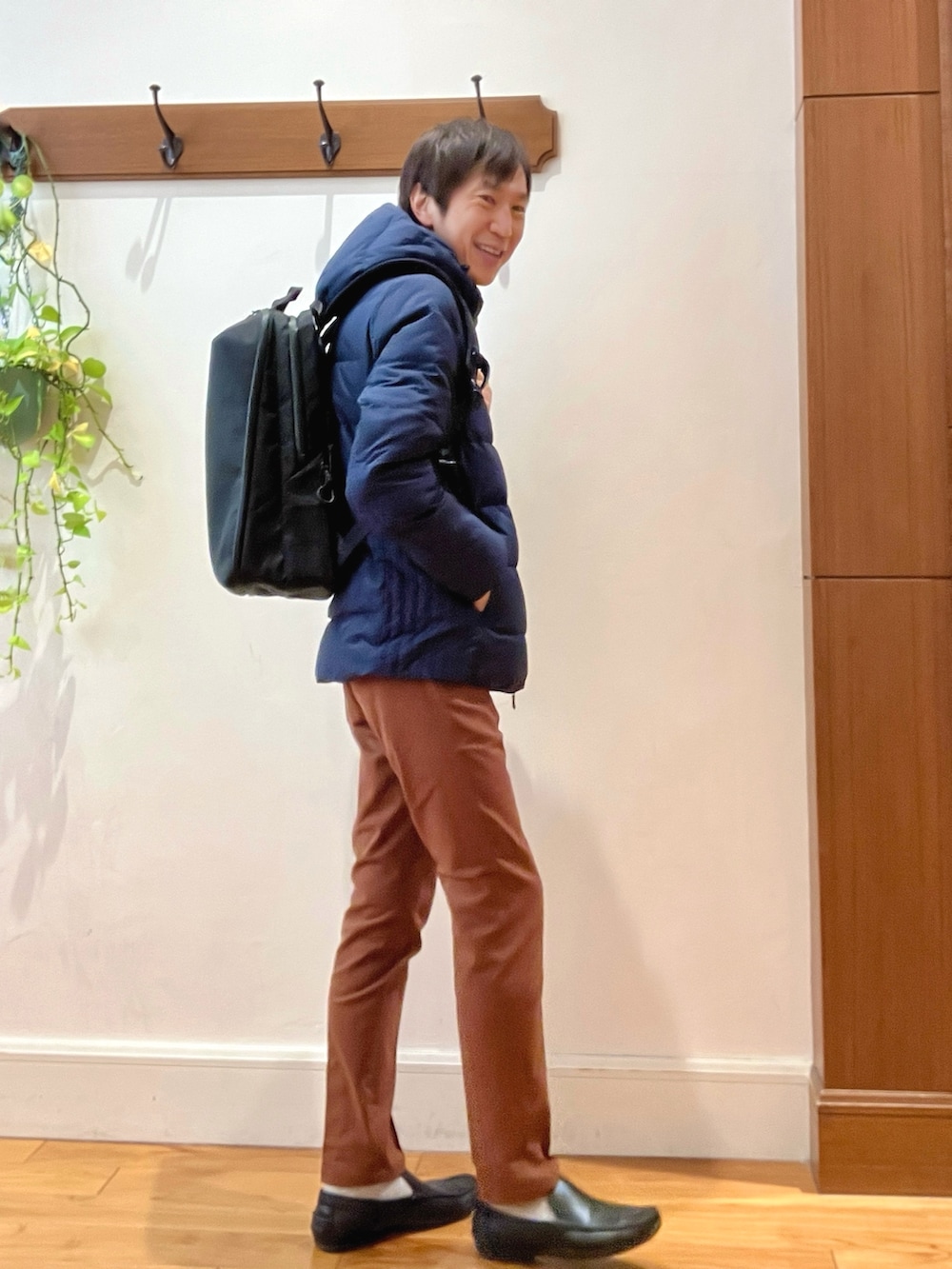 ブルー系のダウンジャケット/コート、イエロー系のチノパンツ、ブラック系のバックパック/リュックを着用したメンズの冬コーディネートの6枚目の写真