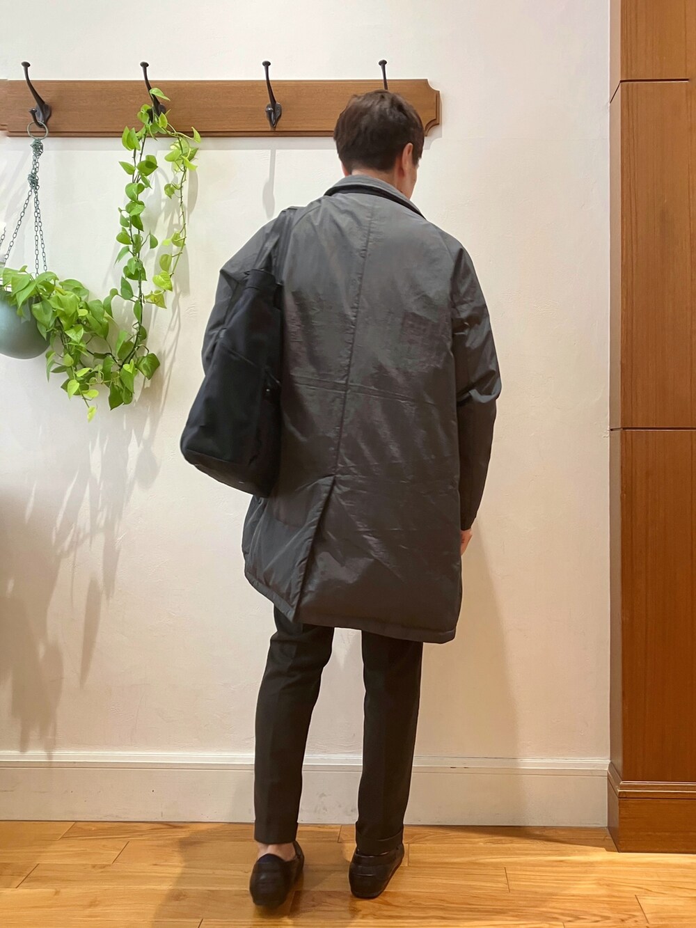 ブラック系のトートバッグ、ブラウン系のスラックス、グレー系のダウンジャケット/コートを着用したメンズの夏コーディネートの6枚目の写真