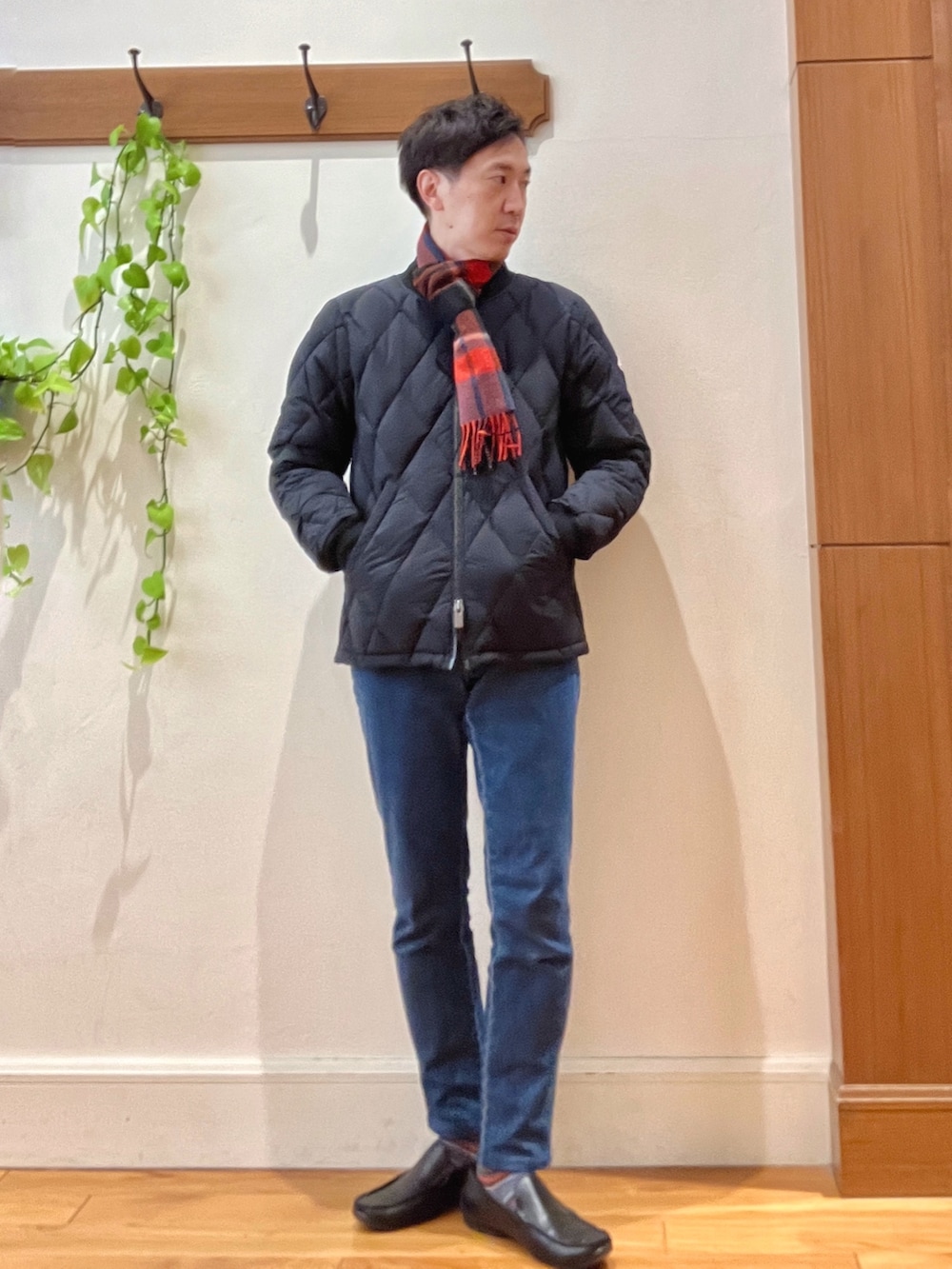 ブラック系のダウンジャケット/コート、ベージュ系のニット/セーター、ブルー系のデニムパンツを着用したメンズの冬コーディネートの7枚目の写真