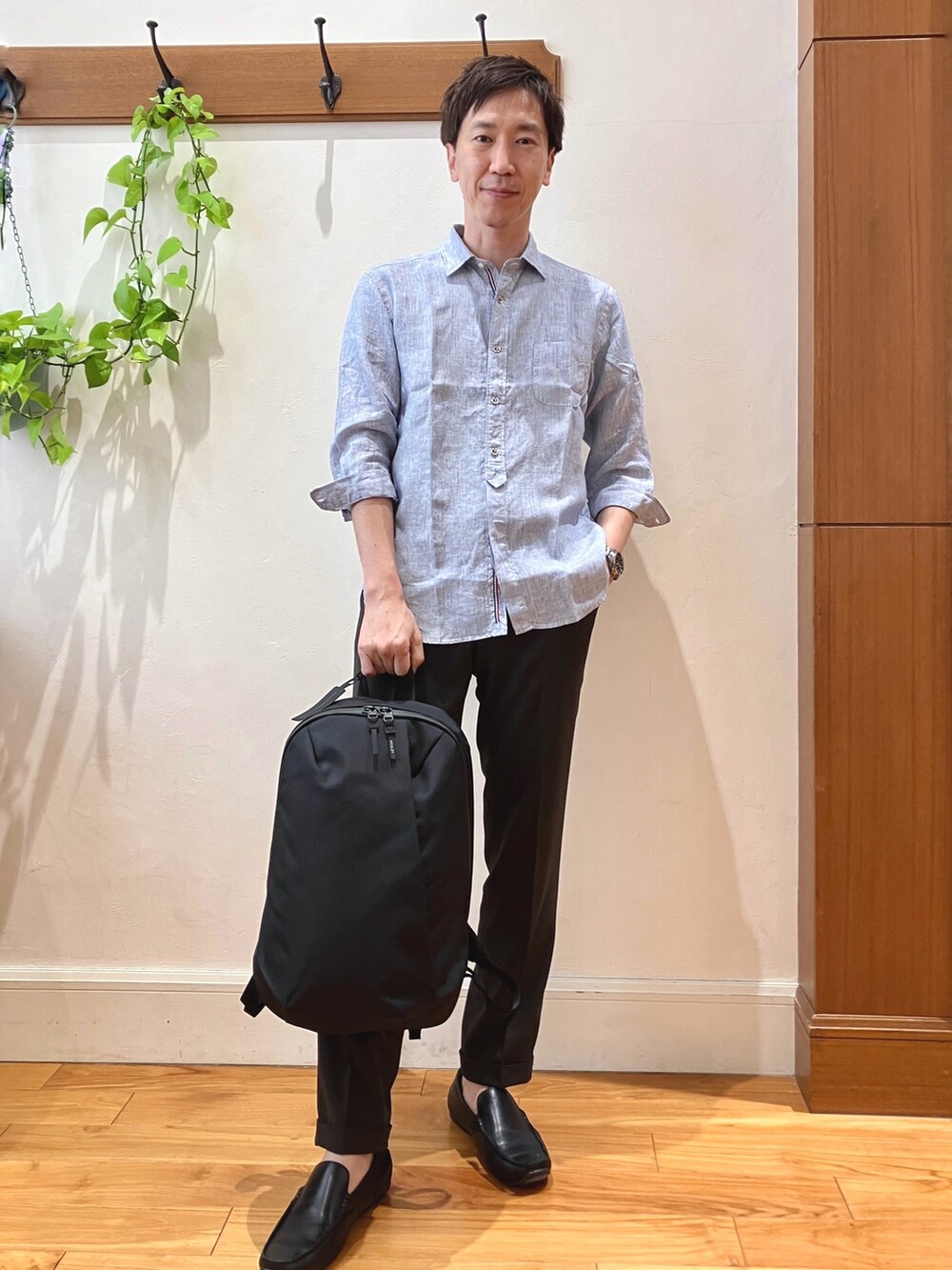 ブルー系のシャツ/ブラウス、ブラウン系のスラックス、ブラック系のバックパック/リュックを着用したメンズの春コーディネートの7枚目の写真