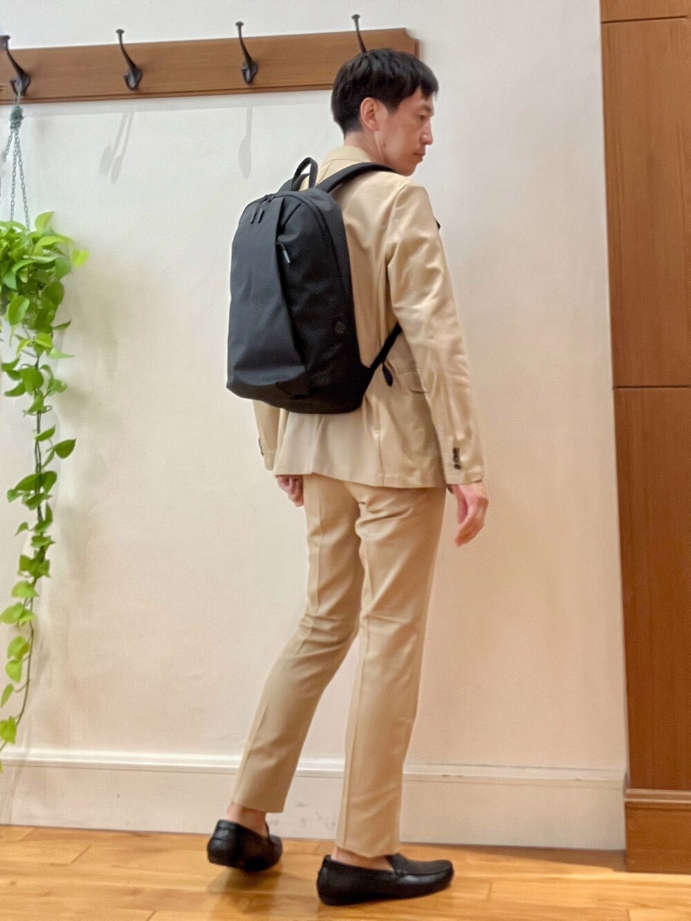 ベージュ系のテーラードジャケット、ブラック系のTシャツ/カットソー、ブラック系のバックパック/リュックを着用したメンズの秋コーディネートの5枚目の写真