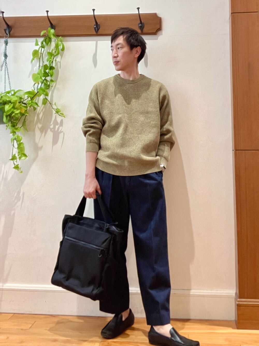 イエロー系のニット/セーター、ブルー系のデニムパンツ、ブラック系のトートバッグを着用したメンズの冬コーディネートの2枚目の写真