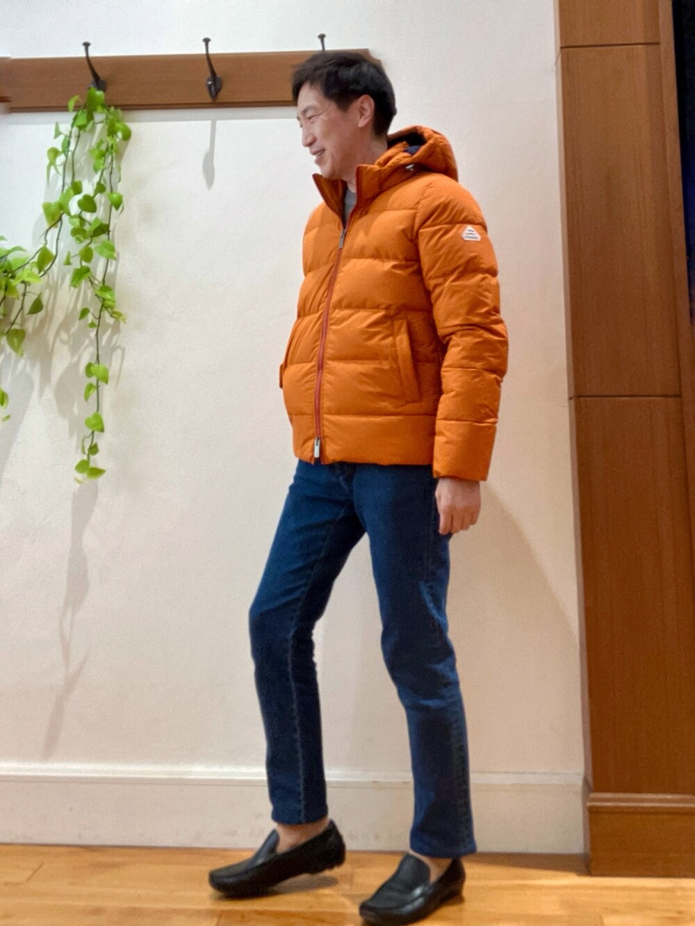 ブルー系のデニムパンツ、ベージュ系のニット/セーター、オレンジ系のダウンジャケット/コートを着用したメンズの冬コーディネートの3枚目の写真
