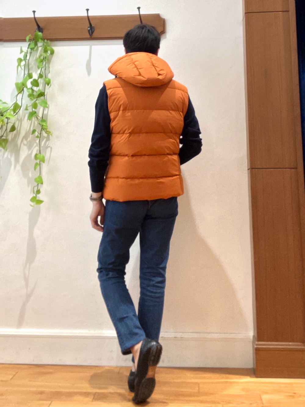 ブルー系のデニムパンツ、ブルー系のニット/セーター、オレンジ系のダウンベストを着用したメンズの冬コーディネートの5枚目の写真