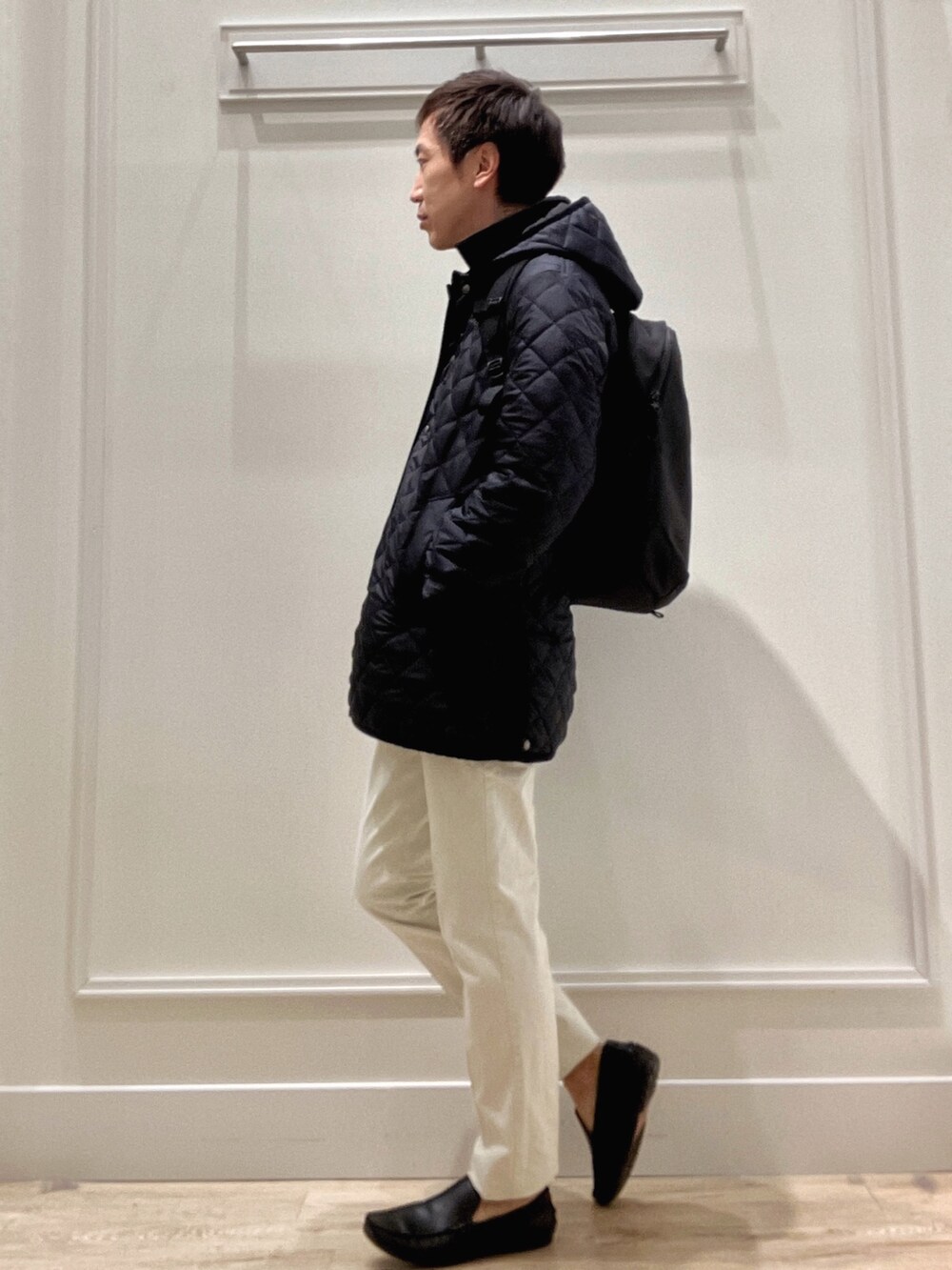 ブルー系のステンカラーコート、ブルー系のニット/セーター、ホワイト系のチノパンツを着用したメンズの冬コーディネートの4枚目の写真