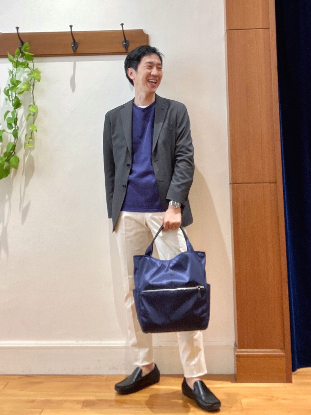 パープル系のニット/セーター、ホワイト系のチノパンツ、ブルー系のトートバッグを着用したメンズの秋コーディネートの2枚目の写真