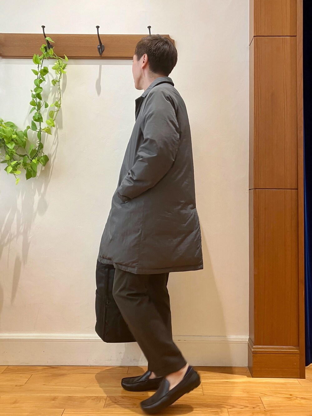 ブラック系のトートバッグ、ブラウン系のスラックス、グレー系のダウンジャケット/コートを着用したメンズの夏コーディネートの5枚目の写真