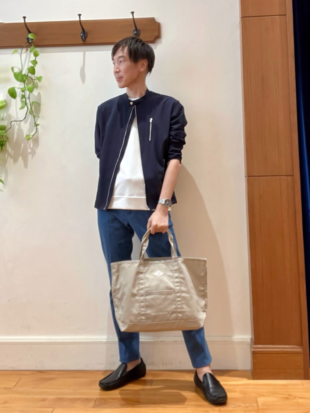 ブルー系のデニムパンツ、ベージュ系のトートバッグ、ホワイト系のTシャツ/カットソーを着用したメンズの秋コーディネートの2枚目の写真