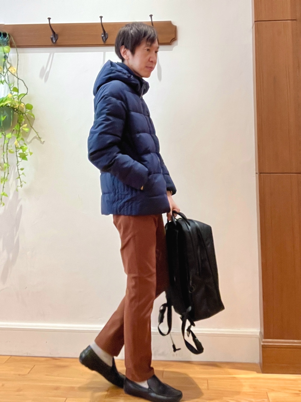 ブルー系のダウンジャケット/コート、イエロー系のチノパンツ、ブラック系のバックパック/リュックを着用したメンズの冬コーディネートの7枚目の写真