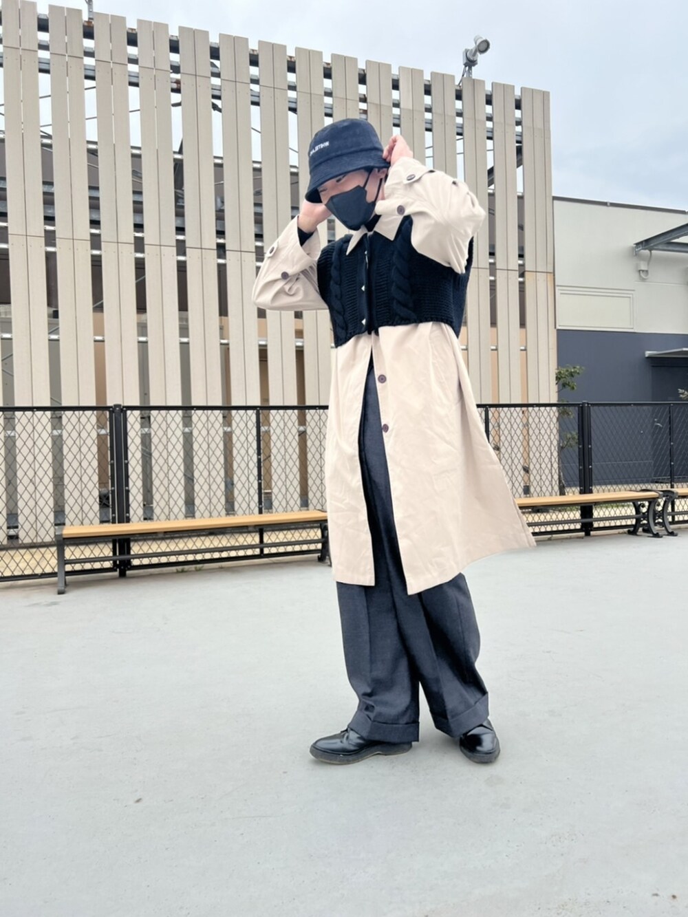 ベージュ系のステンカラーコート、ブラック系のカーディガン/ボレロ、ブラック系のハットを着用したメンズの冬コーディネートの2枚目の写真