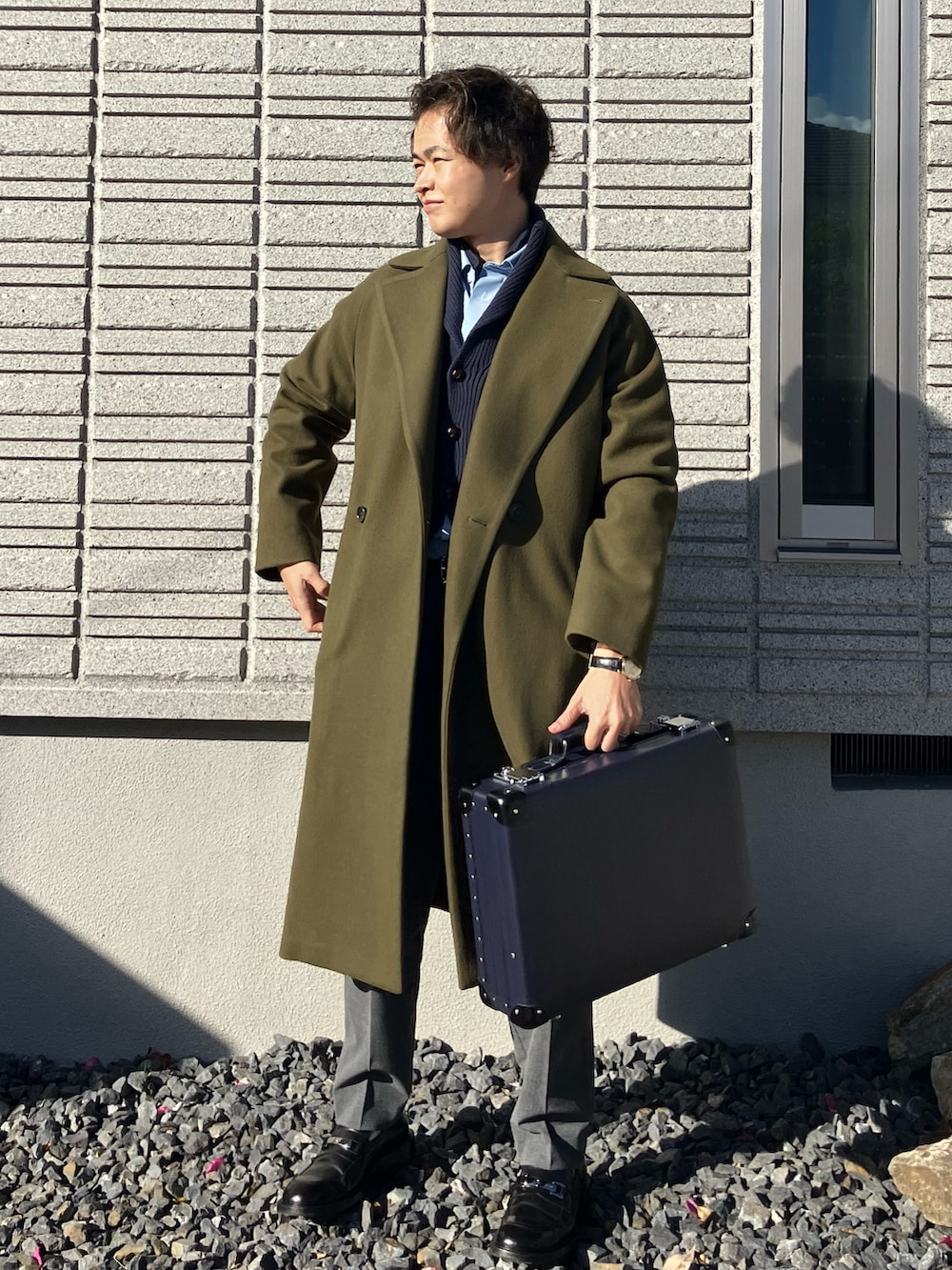 ブルー系のニット/セーター、ブルー系のビジネスシャツ、グリーン系のステンカラーコートを着用したメンズの冬コーディネートの2枚目の写真