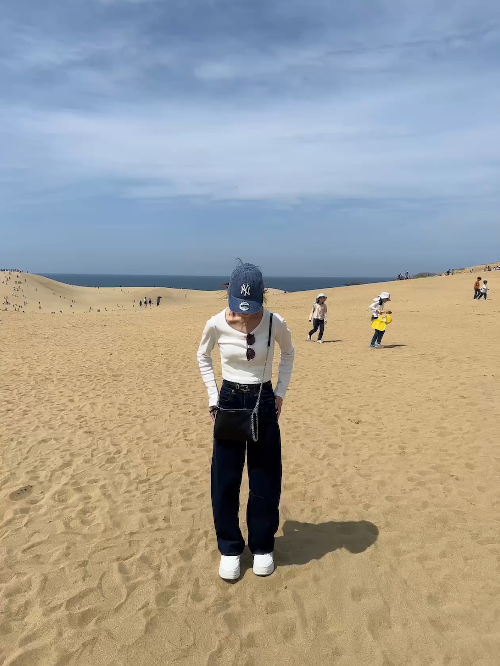 ブルー系のキャップを着用したレディースの春コーディネートの2枚目の写真