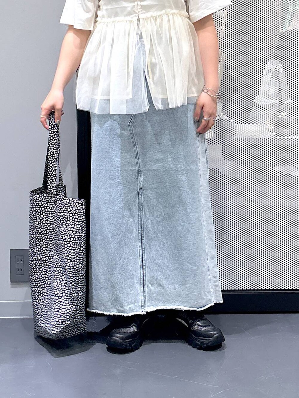 ブラック系のスニーカー、ブルー系のデニムスカート、ホワイト系のTシャツ/カットソーを着用したレディースの春コーディネートの5枚目の写真