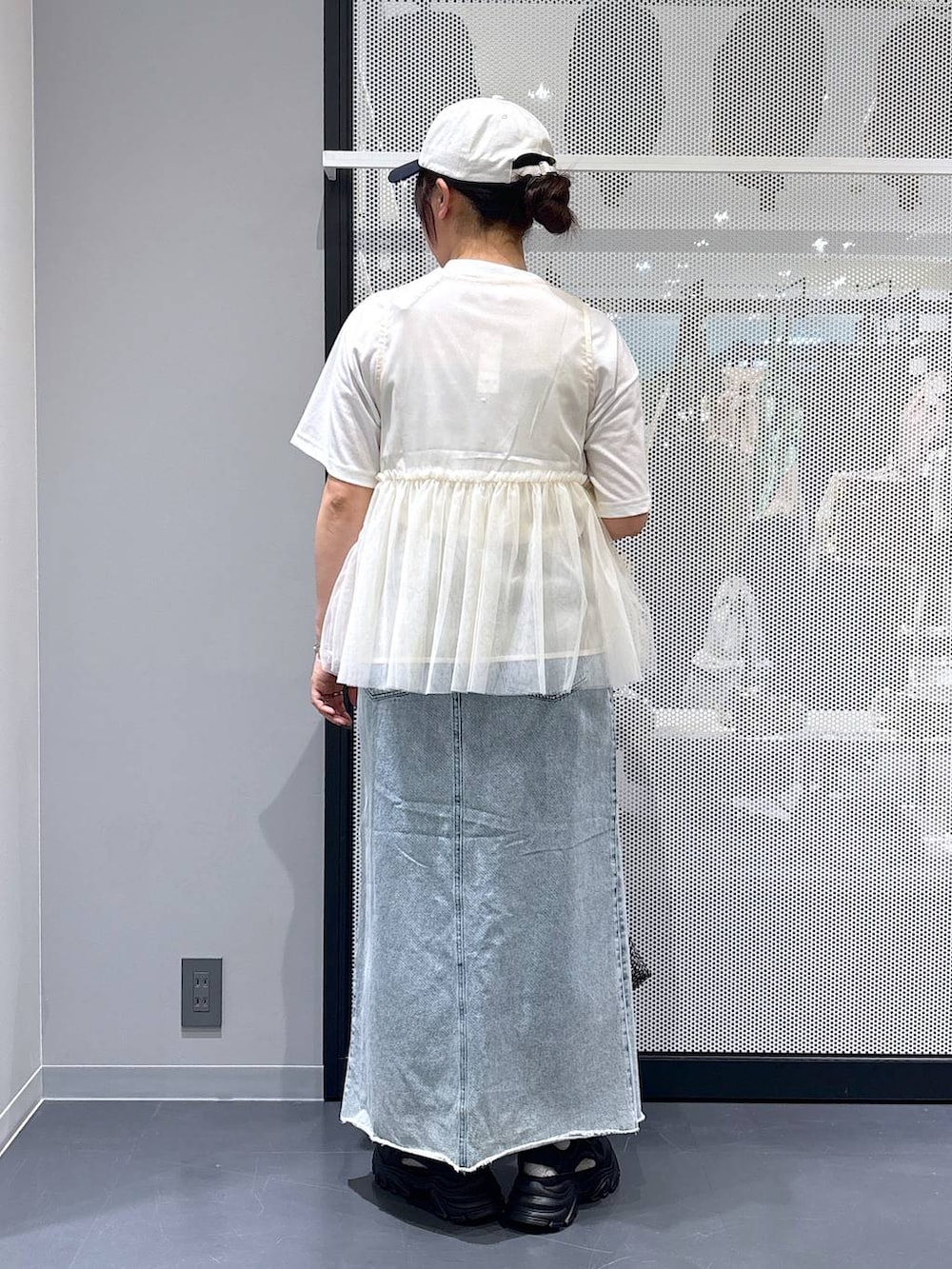 ブラック系のスニーカー、ブルー系のデニムスカート、ホワイト系のTシャツ/カットソーを着用したレディースの春コーディネートの3枚目の写真