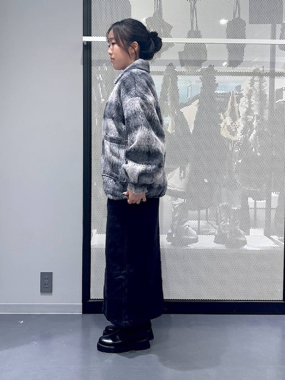 グレー系のジャンパースカート、ブラック系のショルダーバッグ、ブラック系のブーツを着用したレディースの冬コーディネートの2枚目の写真