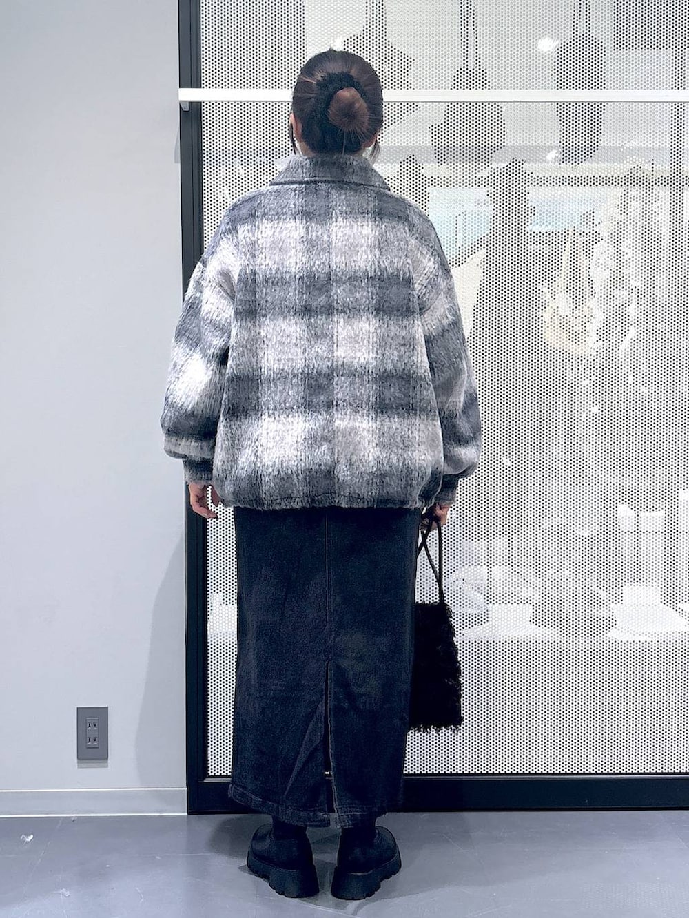 グレー系のジャンパースカート、ブラック系のショルダーバッグ、ブラック系のブーツを着用したレディースの冬コーディネートの3枚目の写真