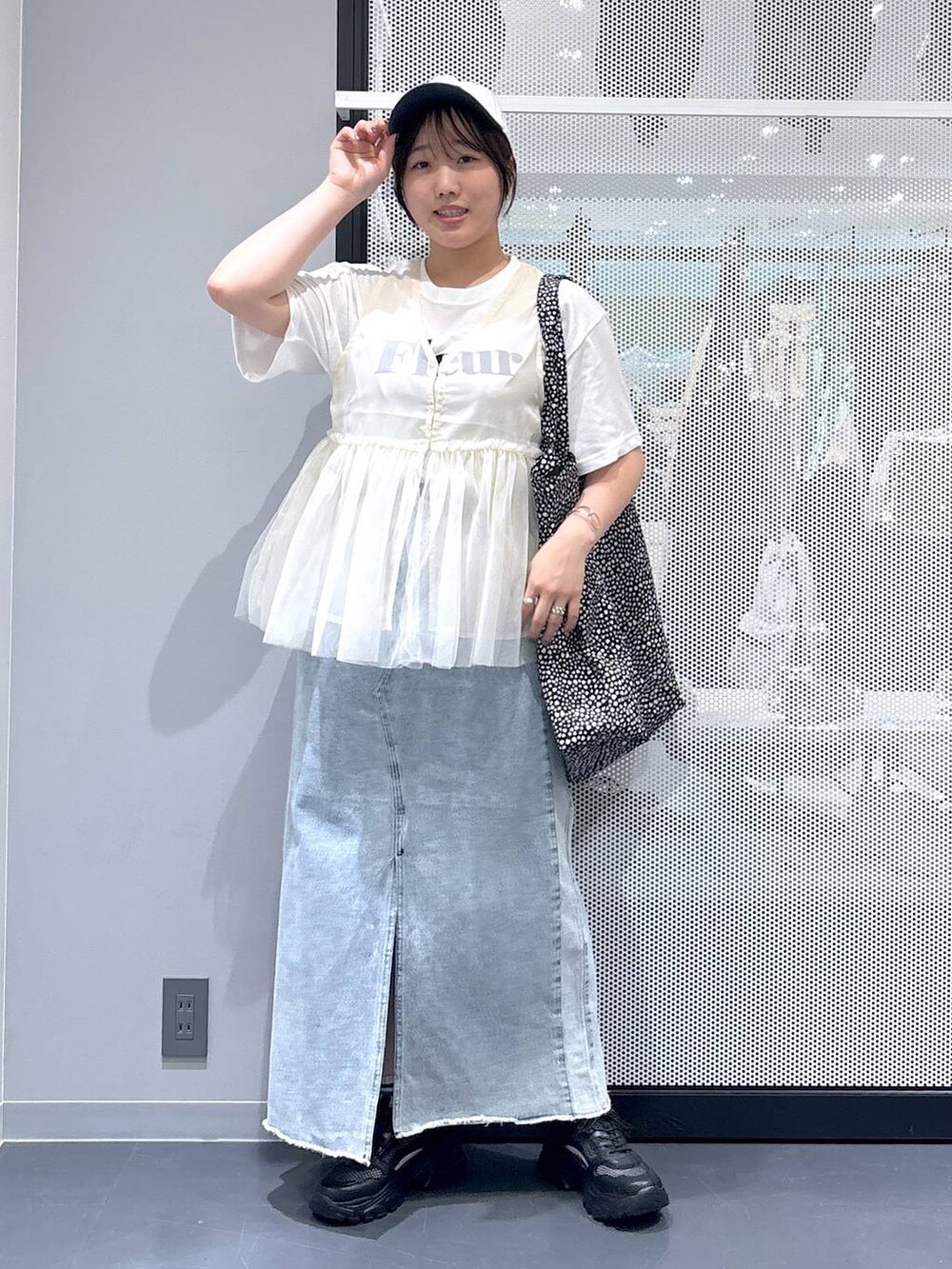 ブラック系のスニーカー、ブルー系のデニムスカート、ホワイト系のTシャツ/カットソーを着用したレディースの春コーディネートの6枚目の写真