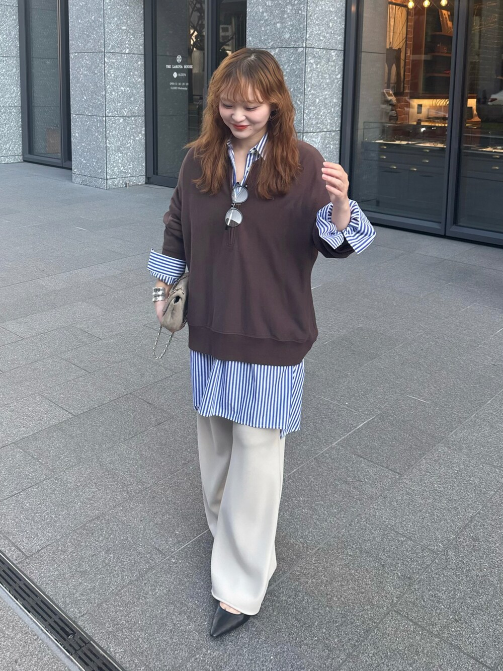 ブラウン系のスウェット、ブルー系のシャツ/ブラウス、ホワイト系のスラックスを着用したレディースの冬コーディネートの2枚目の写真