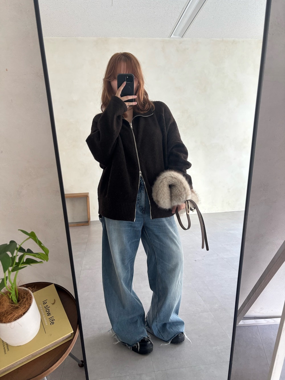 ホワイト系のトートバッグ、ブルー系のデニムパンツ、ブラウン系のカーディガン/ボレロを着用したレディースの秋コーディネートの2枚目の写真