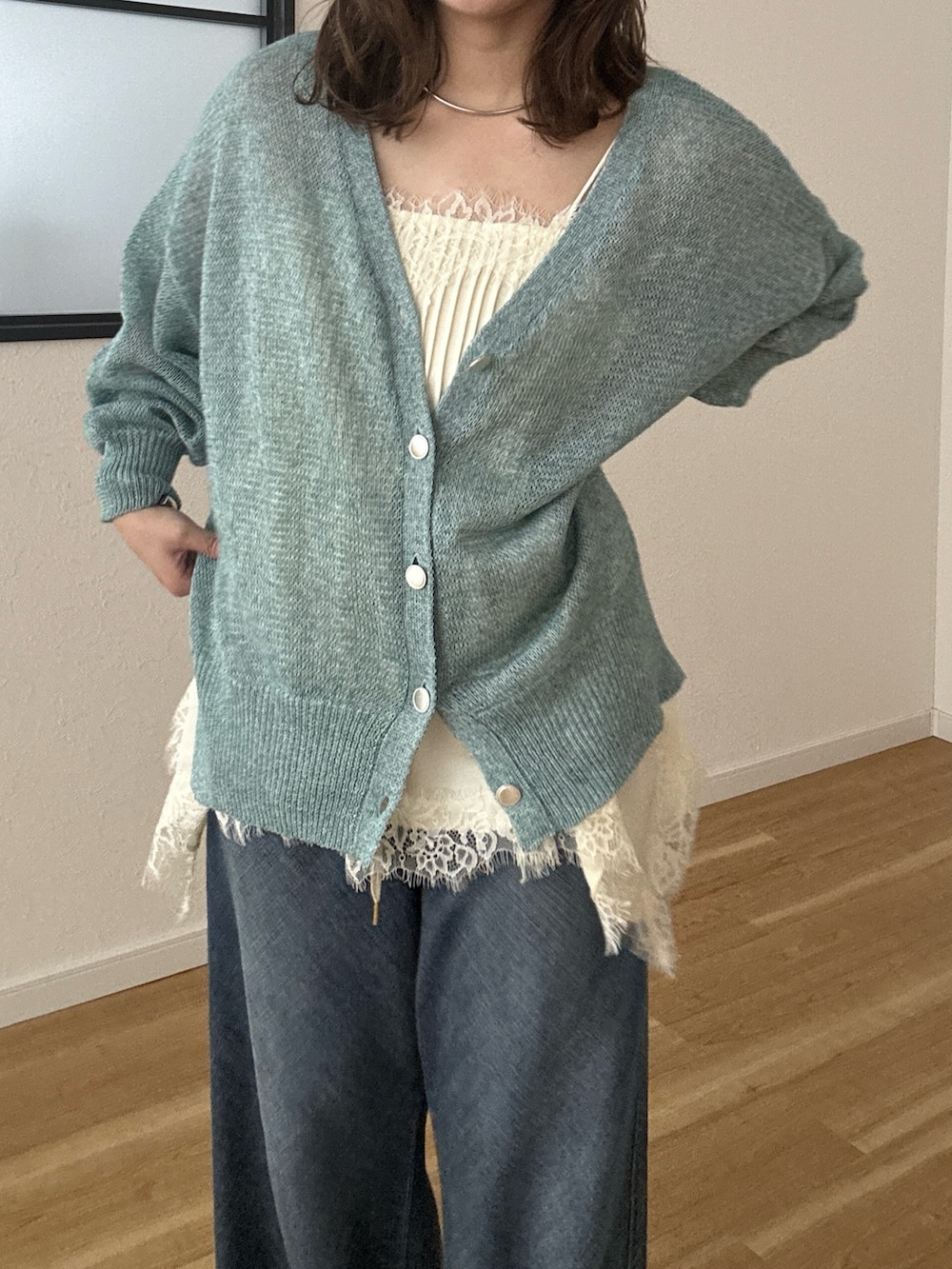 グリーン系のカーディガン/ボレロ、ブルー系のデニムパンツを着用したレディースの春コーディネートの2枚目の写真