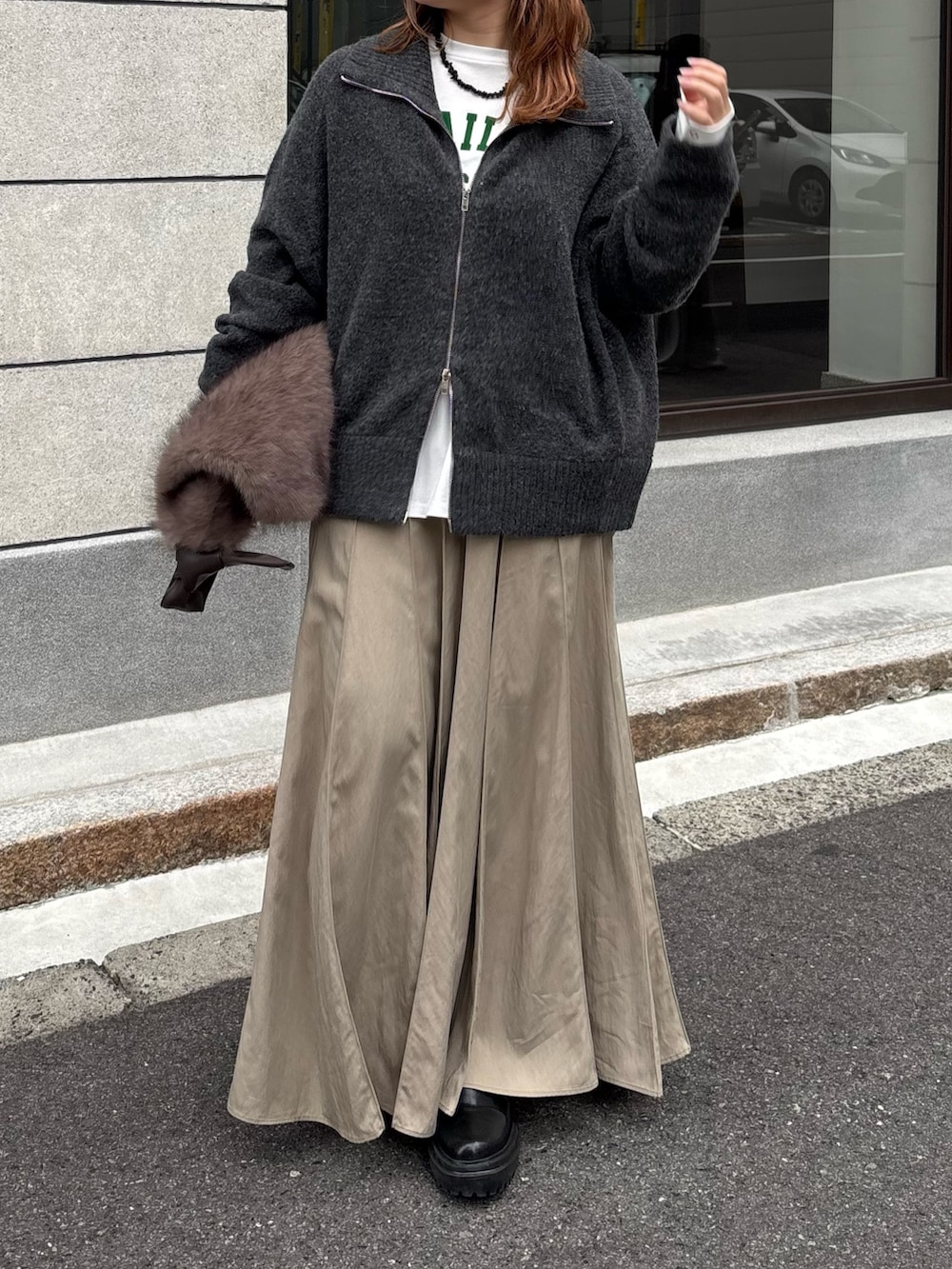 グレー系のカーディガン/ボレロ、ベージュ系のスカート、ブラウン系のショルダーバッグを着用したレディースの秋コーディネートの3枚目の写真