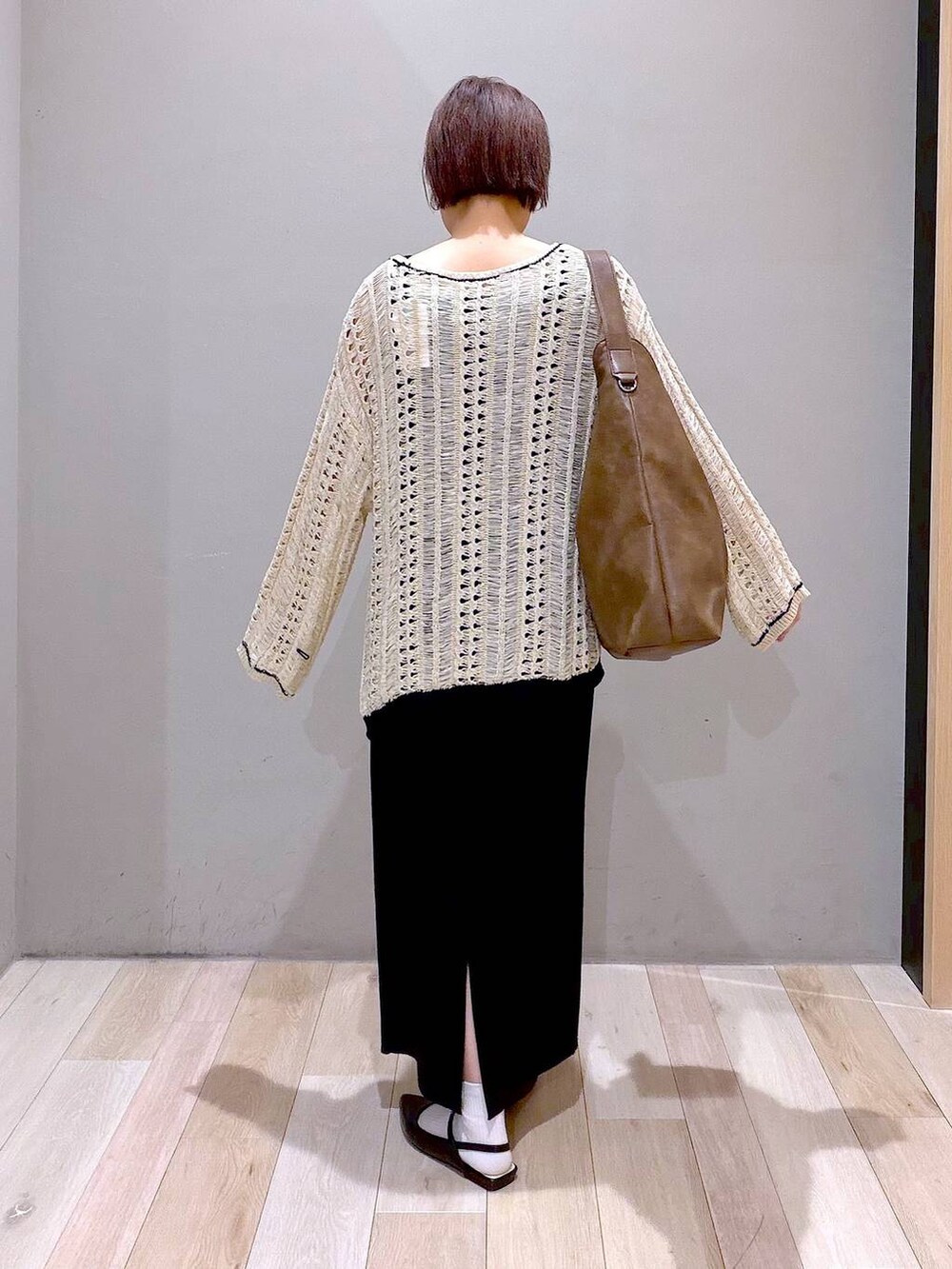 ブラック系のスカート、ブラウン系のショルダーバッグ、ブラック系のパンプスを着用したレディースの春コーディネートの6枚目の写真