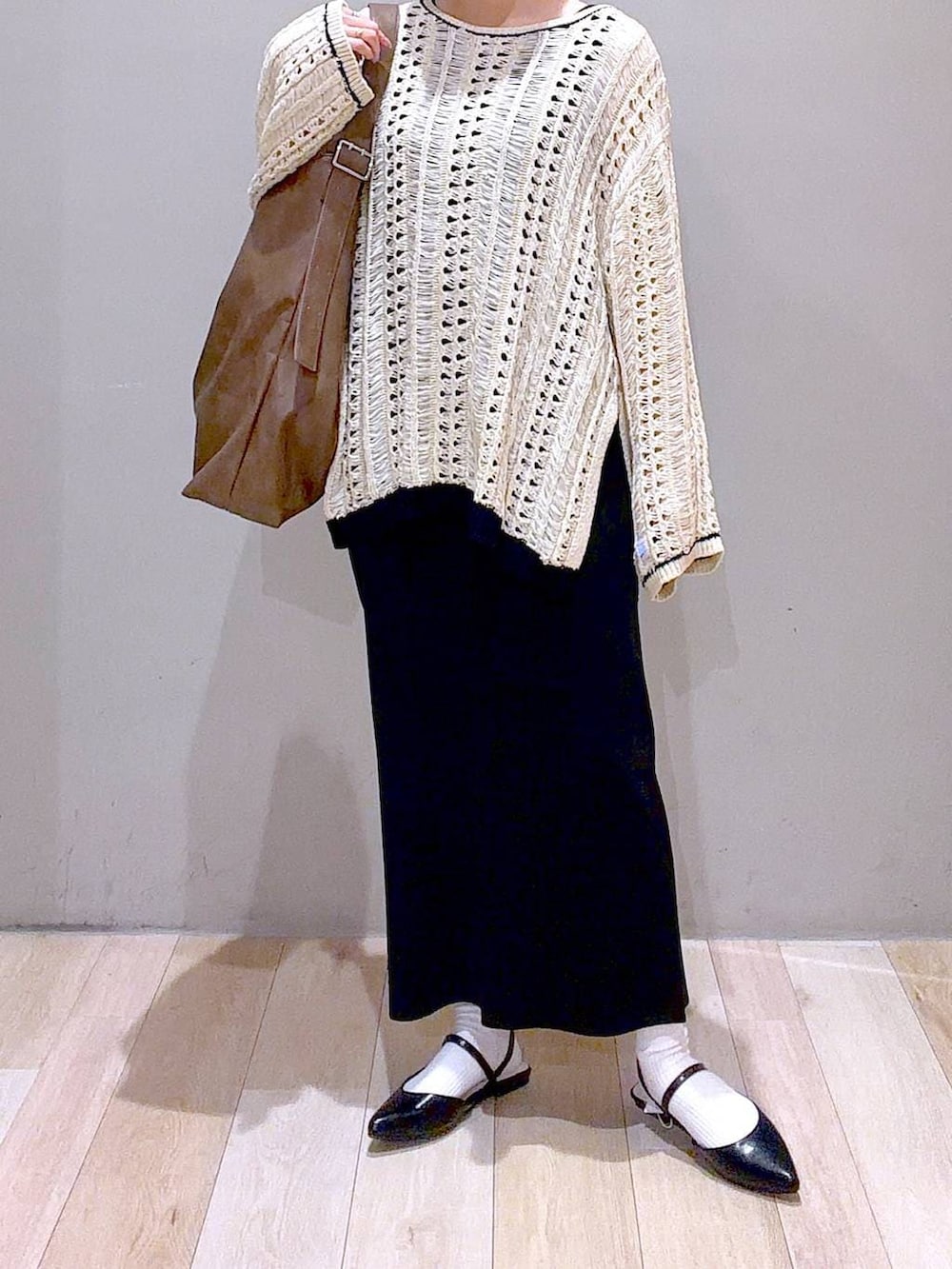 ブラック系のスカート、ブラウン系のショルダーバッグ、ブラック系のパンプスを着用したレディースの春コーディネートの4枚目の写真