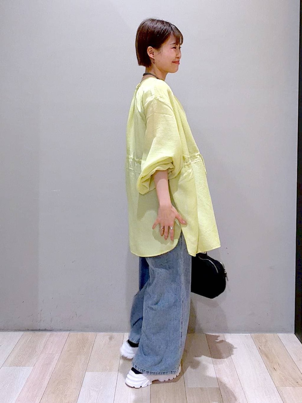 ブルー系のサロペット/オーバーオール、イエロー系のシャツ/ブラウス、ブラック系のボストンバッグを着用したレディースの春コーディネートの2枚目の写真