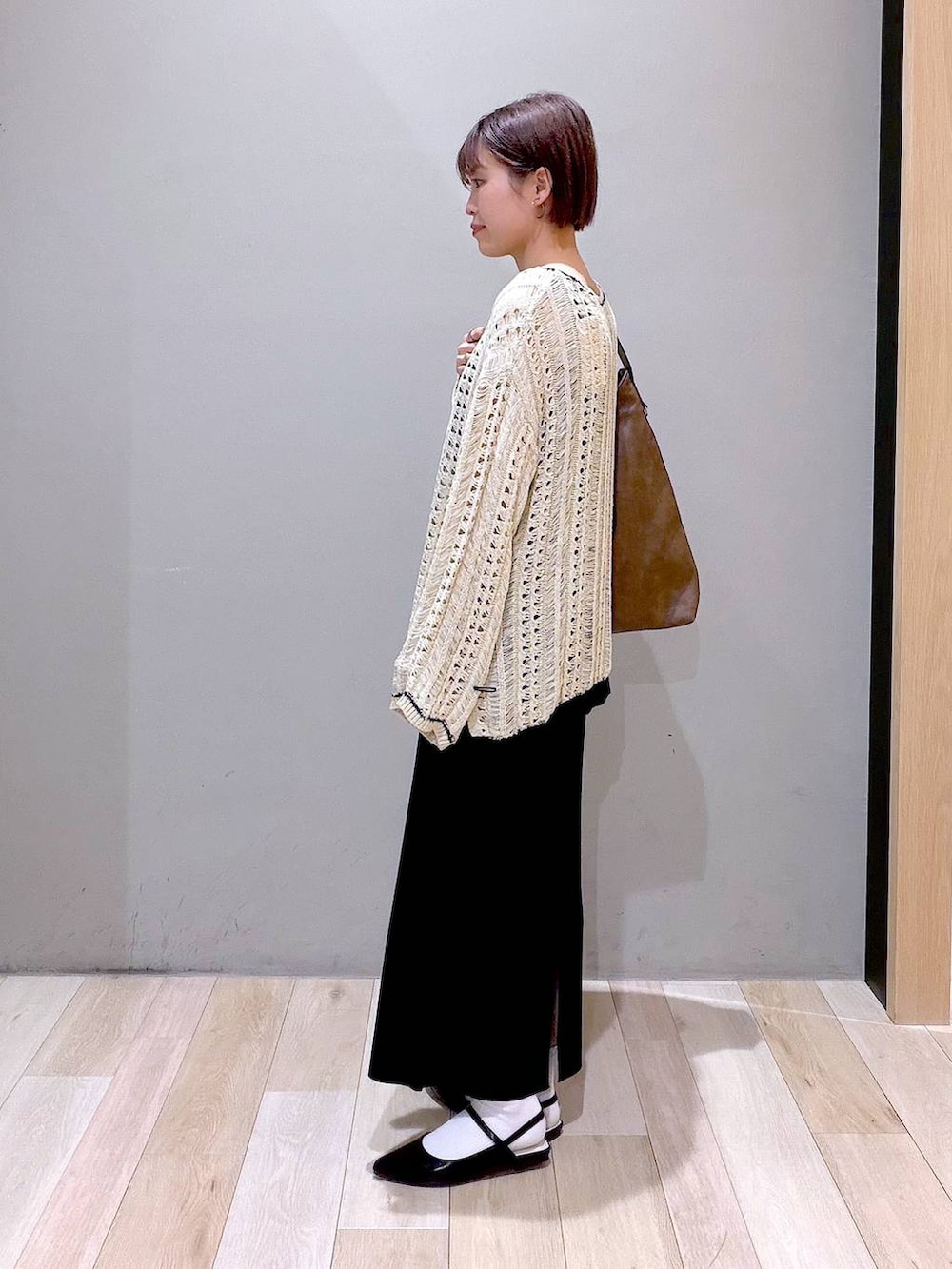 ブラック系のスカート、ブラウン系のショルダーバッグ、ブラック系のパンプスを着用したレディースの春コーディネートの5枚目の写真