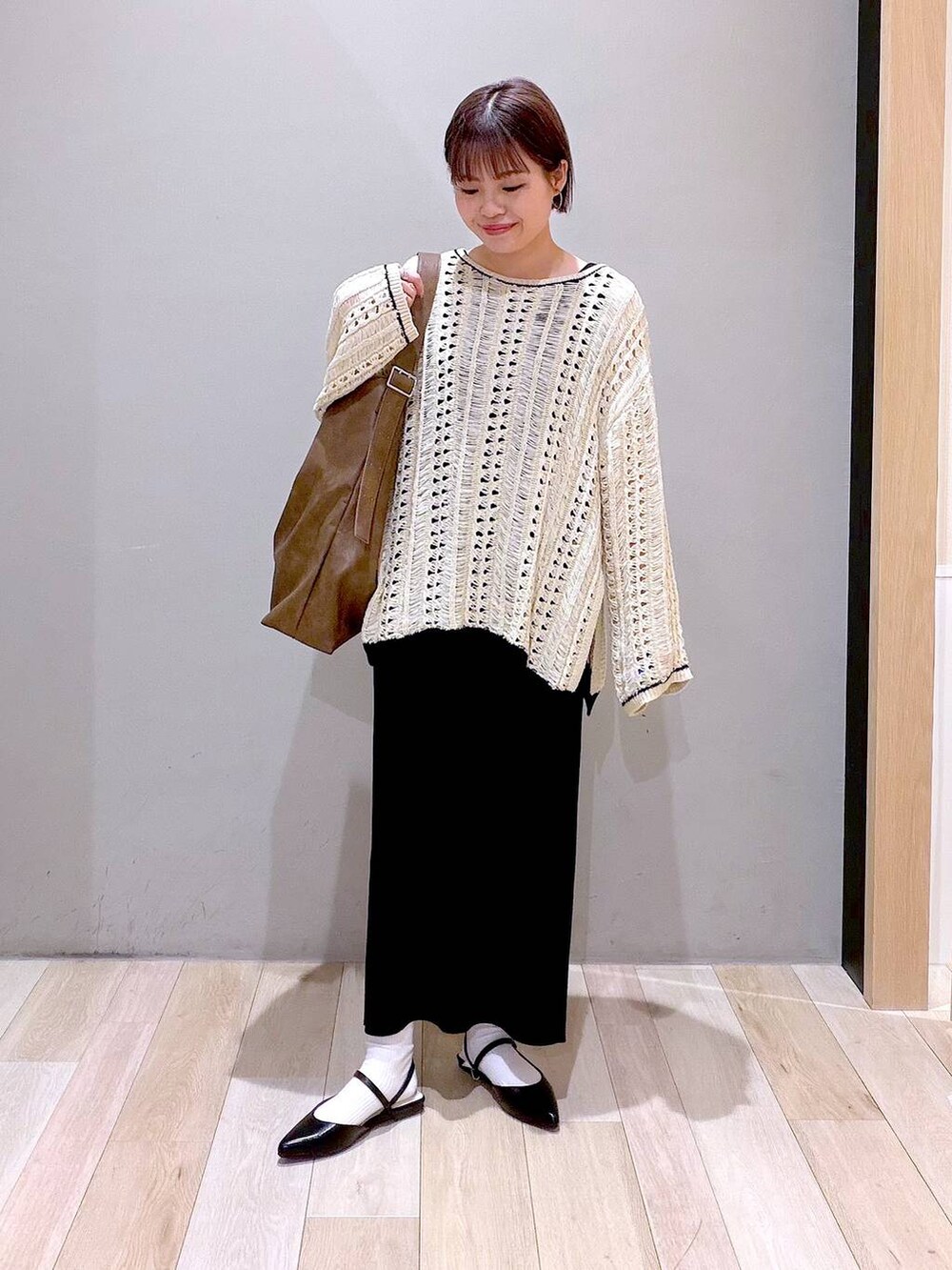 ブラック系のスカート、ブラウン系のショルダーバッグ、ブラック系のパンプスを着用したレディースの春コーディネートの2枚目の写真